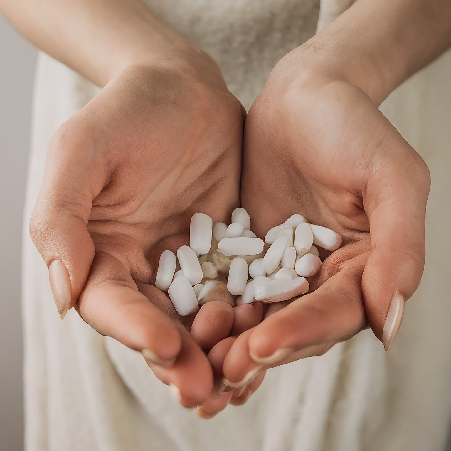 Close-up of a woman holding white sleeping pills in cupped hands, representing sleep medication and insomnia treatment.
